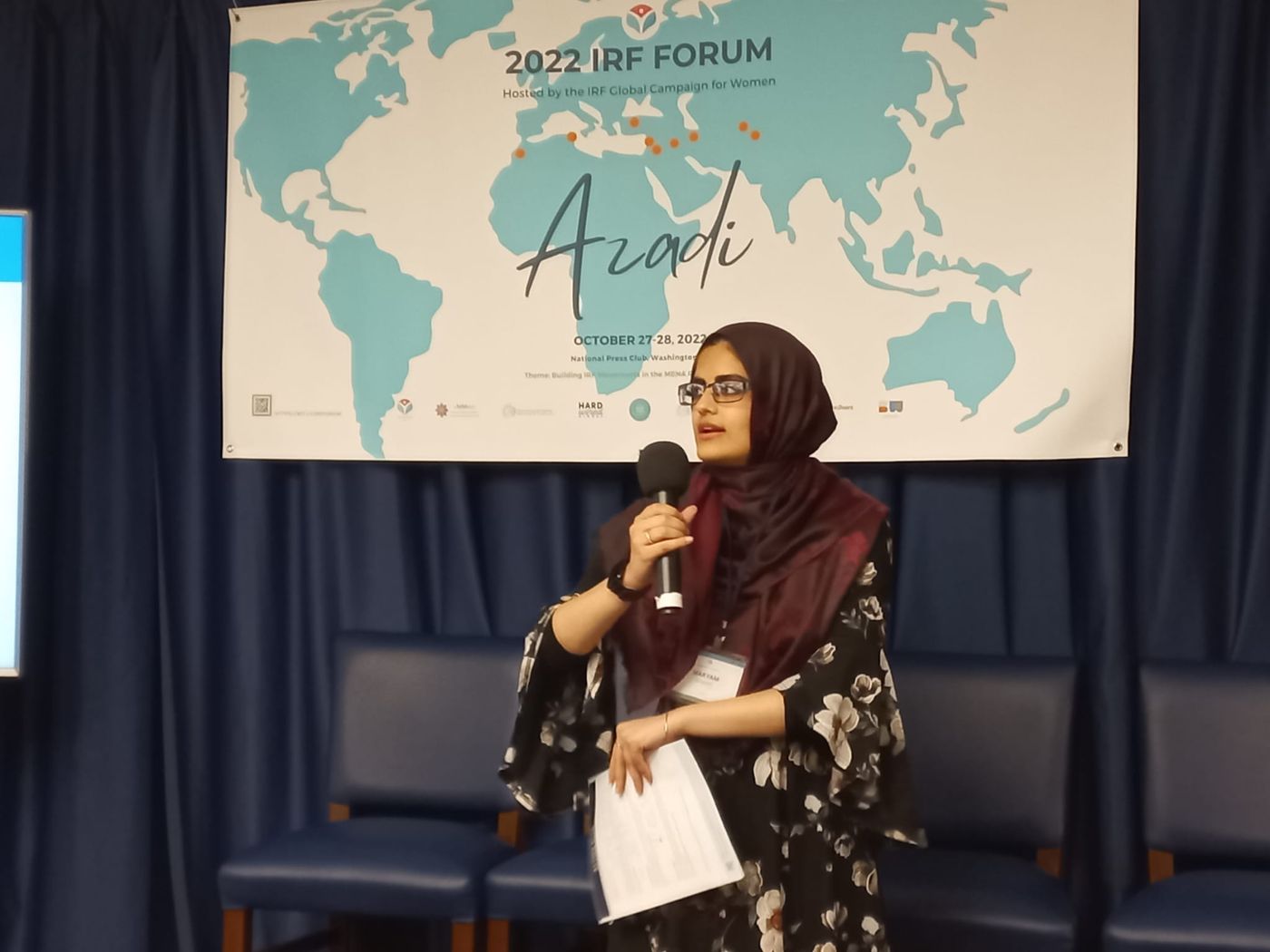 Maryam speaking before a world map